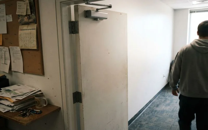 A close-up of a fire door's self-closing hinge mechanism and door seal in a Singapore condo common corridor